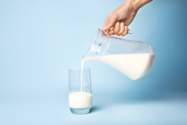 Woman pouring milk into glass on color background - Foto, imagen