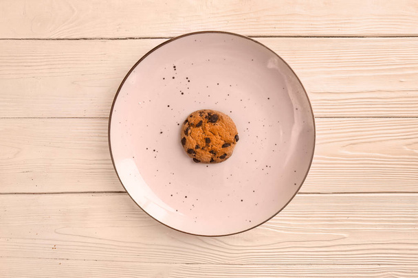 Plate with tasty cookie on light wooden background - 写真・画像