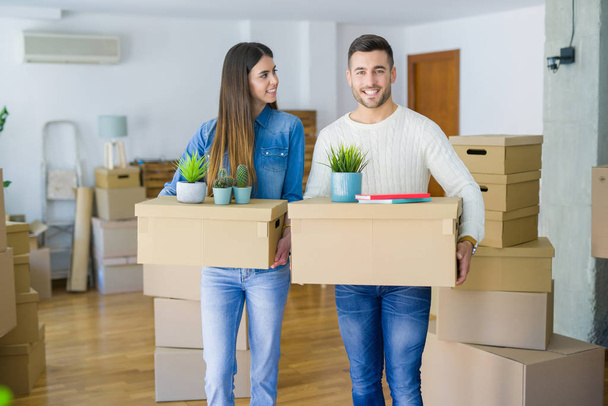 Giovane coppia che si trasferisce in una nuova casa, sorridente felice in possesso di scatole di cartone al nuovo appartamento
 - Foto, immagini