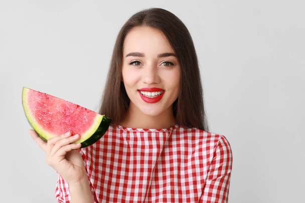 Beautiful young woman with slice of fresh watermelon on light background - Foto, imagen