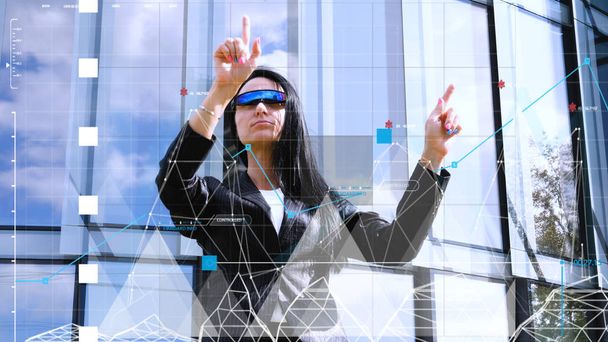 virtuelle holographische Oberfläche und junge Frau mit Brille, erfolgreiche Geschäftsfrau mit Virtual-Reality-Brille, während sie mit virtuellem Bildschirm arbeitet. Konzept von: Zukunft, Wolkenkratzer, Infografik. - Foto, Bild