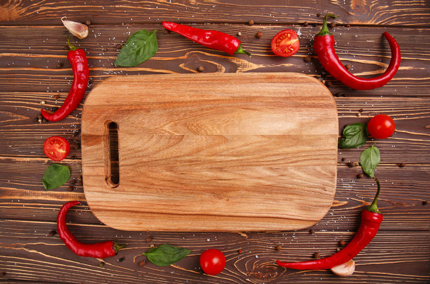 Cutting board, chili peppers and spices on wooden background - Photo, Image