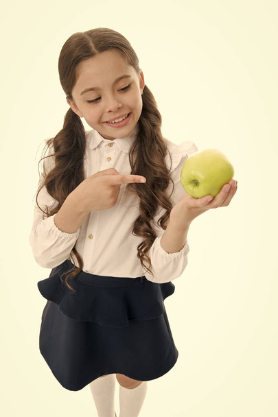 Detox and diet. Girl pupil hold apple fruit on white background. Healthy nutrition diet, Kid happy hold apple. School snack concept. Apple vitamin snack. Schoolgirl wear formal uniform hold apple - Foto, afbeelding