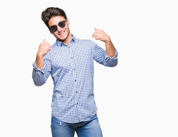Mladý pohledný muž nosí sluneční brýle izolované pozadí sebevědomým úsměvem na tváři, polohovací sebe prsty hrdý a šťastný. - Fotografie, Obrázek