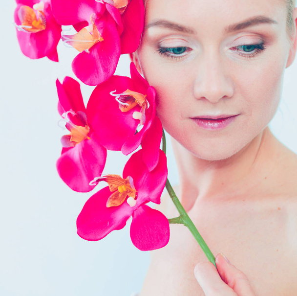 Young beauty woman with flower near face. - Φωτογραφία, εικόνα