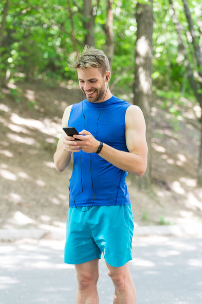 Set up application. Sportsman with smartphone and smart watch prepare for jog. Training with sport application is more fun. Create route run using application. Man smartphone ready to start jog - Фото, изображение