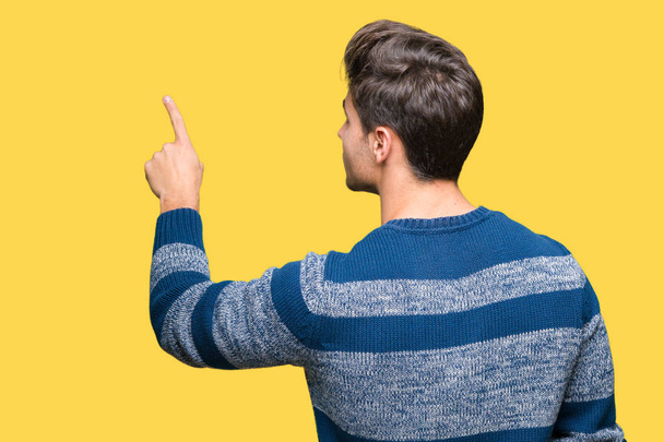 Young handsome man over isolated background Posing backwards pointing behind with finger hand - Foto, imagen