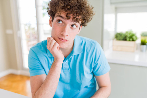 Young handsome man wearing casual blue t-shirt at home thinking looking tired and bored with depression problems with crossed arms. - Foto, Imagen