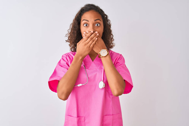 Young brazilian nurse woman wearing stethoscope standing over isolated white background shocked covering mouth with hands for mistake. Secret concept. - Фото, изображение