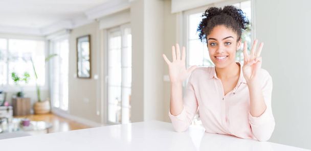 Afro saç gösteren ve parmakları ile işaret eden güzel afro-amerikan kadın geniş açı emin ve mutlu gülümserken sekiz numaralı parmaklar ile. - Fotoğraf, Görsel