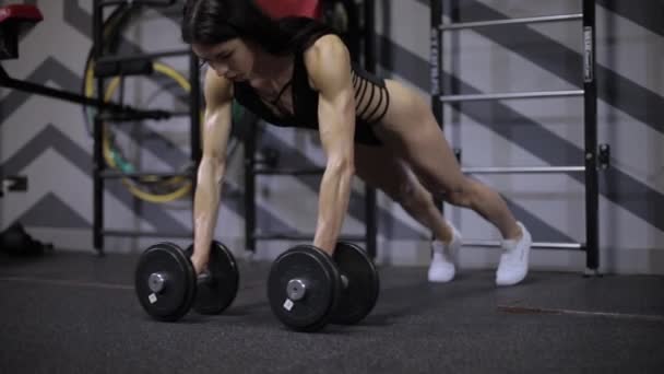 Athletic girl performs strength push-ups from the floor with dumbbells. - Πλάνα, βίντεο