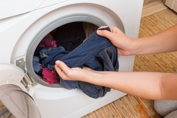 Woman pulls the Laundry out of the washing machine - Фото, изображение
