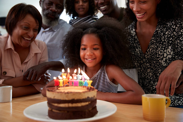 Famille multi-génération célébrant l'anniversaire de la petite-fille à la maison avec gâteau et bougies
 - Photo, image
