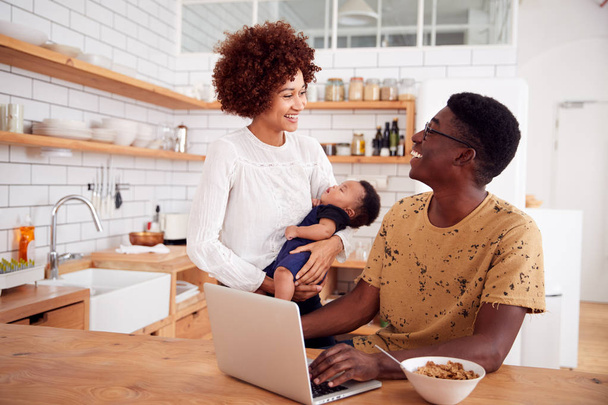 Busy Family In Kitchen At Breakfast With Father Caring For Baby Son - Photo, Image