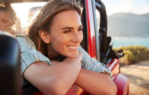 Millennial white woman on a road trip with friends leaning on car door enjoying view, close up - Фото, зображення