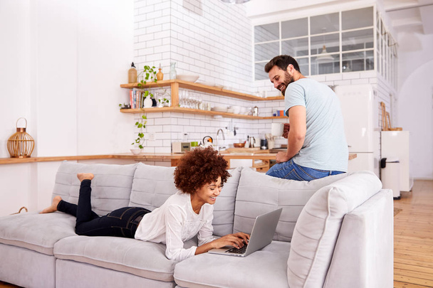 Couple Relaxing On Sofa At Home Looking At Laptop Together - Photo, Image