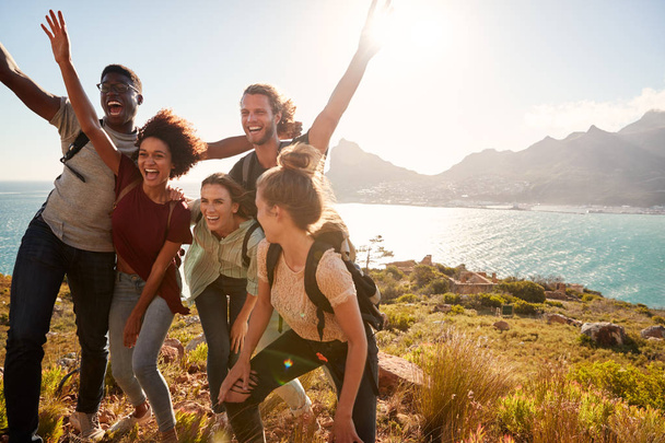 Millennial friends on a hiking trip celebrate reaching the summit and have fun posing for photos - Foto, Imagen