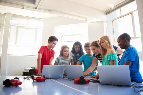 Grupo de estudiantes en clase de codificación de computadora después de la escuela aprendiendo a programar un vehículo robótico
 - Foto, imagen