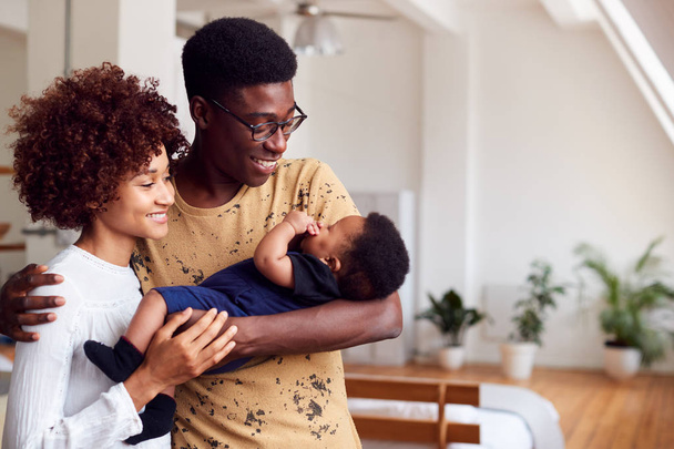 Loving Parents Holding Newborn Baby At Home In Loft Apartment - Foto, afbeelding