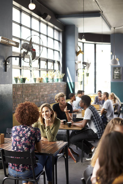 Εσωτερικό της πολυάσχολης καφετέρια με τους πελάτες που κάθονται σε τραπέζια - Φωτογραφία, εικόνα