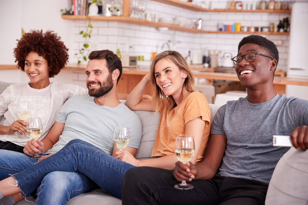 Skupina přátel sedícího na pohovce a sledování filmu doma zatímco pití vína - Fotografie, Obrázek