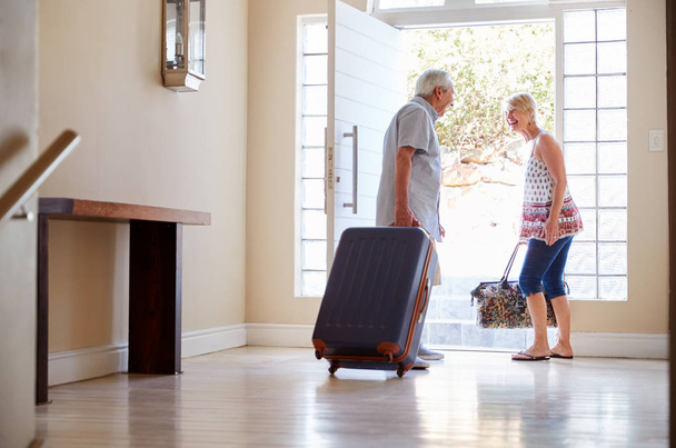 Senior Couple Standing By Front Door With Suitcase About To Leave For Vacation - Фото, изображение