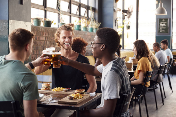 Three Young Male Friends Meeting For Drinks And Food Making A To - Fotó, kép