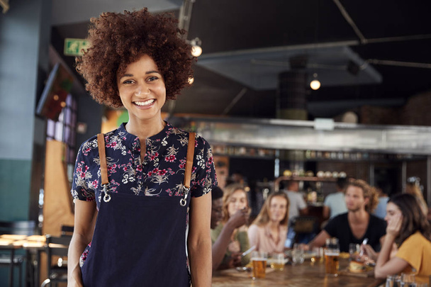 Portrait Of Waitress Serving In Busy Bar Restaurant - Photo, image