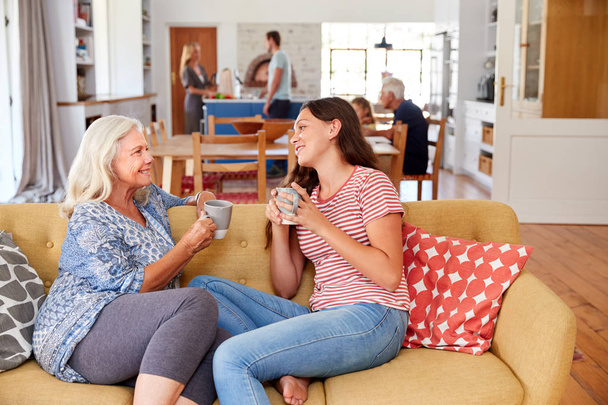 Grandmother With Teenage Granddaughter Relaxing On Sofa And Talking At Home - Photo, Image