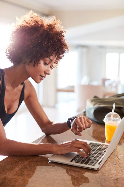 Millennial African American woman checking fitness app on watch and laptop after workout, vertical - Foto, Imagen