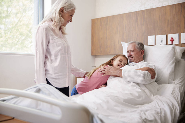 Granddaughter Hugging Grandfather On Family Hospital Visit - Valokuva, kuva