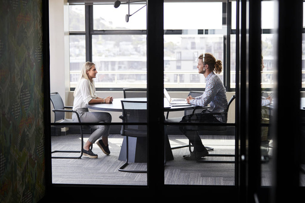 Two millennial business creatives in a meeting room for a job interview, seen through glass wall - Fotoğraf, Görsel