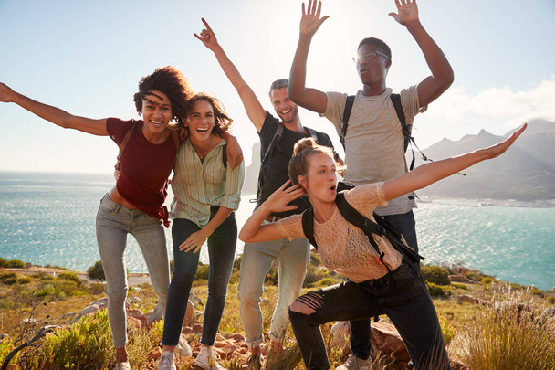 Millennial friends on a hiking trip celebrate reaching the summit and have fun posing for photos - Photo, image