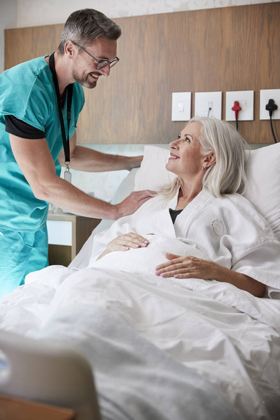 Surgeon Visiting And Talking With Mature Female Patient In Hospital Bed - Zdjęcie, obraz