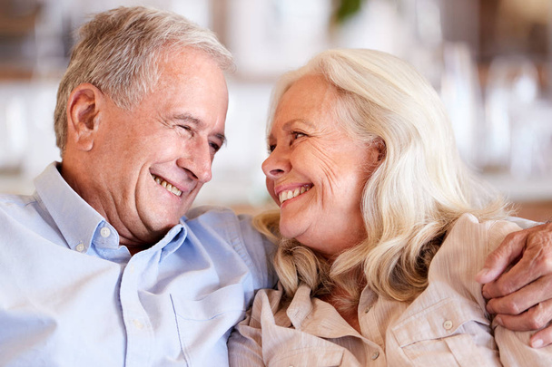 Happy senior white couple sit at home embracing, smiling at each other, head and shoulders, close up - Photo, Image