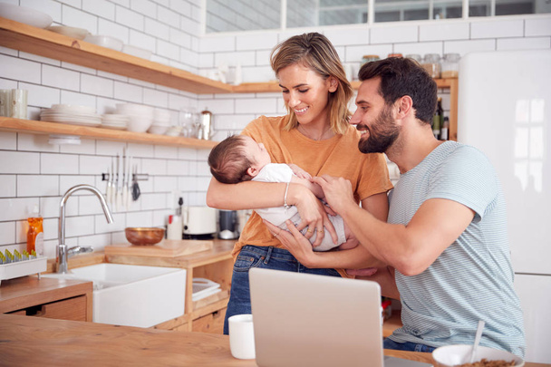 Busy Family In Kitchen At Breakfast With Mother Caring For Baby Son - Photo, image