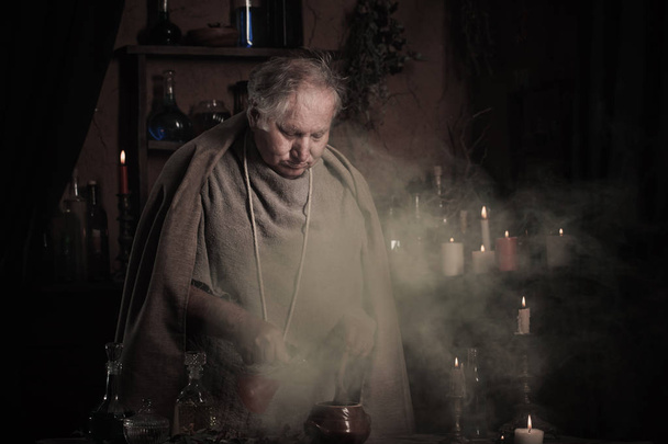 elderly alchemist monk brews  magic potion - Foto, afbeelding