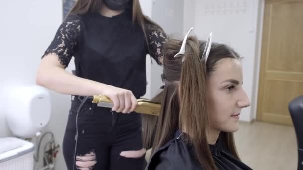 Kadeřník dělá v kadeřnictví krásné vlasy pro dívku s brunetou. koncepce péče o vlasy. - Záběry, video