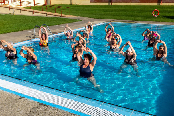 Groupe de femmes âgées faisant des exercices d "échauffement dans une piscine extérieure. - Photo, image