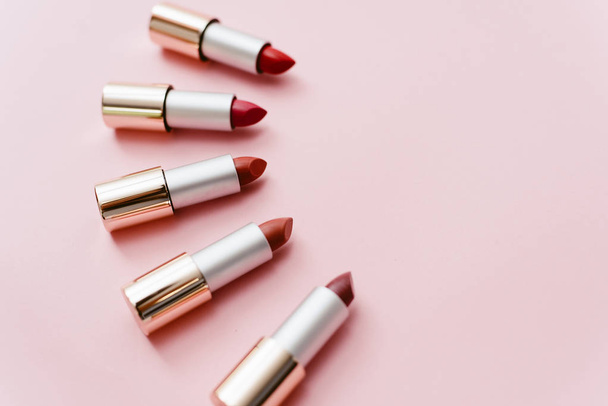 Lipsticks in verschillende tinten roze en rood liggen op een pastel roze achtergrond. Copyspace, bovenaanzicht - Foto, afbeelding