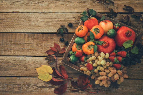 Vintage wooden tray with autumn fruits on rustic vintage table top view. Cozy lifestyle. Fresh organic fruits. Food background. Healthy food. - Foto, Imagen