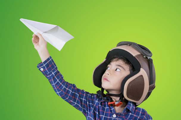 Mały chłopiec nosi kask podczas gry samolot papieru - Zdjęcie, obraz