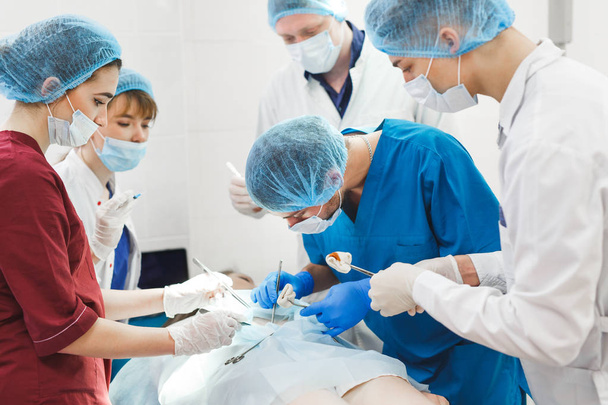 Grupa chirurgów pracujących w teatrze chirurgicznym. Zespół medycyny reanimacyjnej w maskach ochronnych z narzędziami medycznymi ze stali - Zdjęcie, obraz