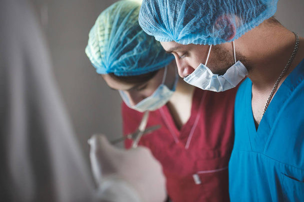 Chirurgen aan het werk in de operatiekamer. Reanimatie medische team dragen beschermende maskers met stalen medische hulpmiddelen - Foto, afbeelding
