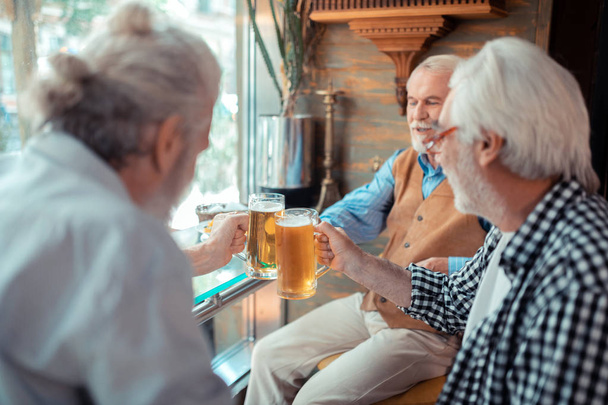 Bearded grey-haired men clanging glasses with beer - Φωτογραφία, εικόνα