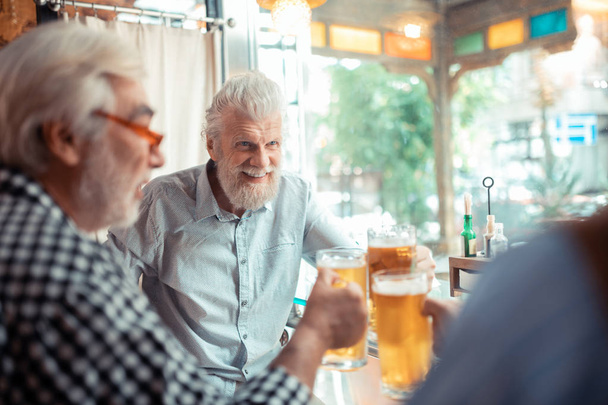 Man smiling while drinking beer with friends - Photo, Image