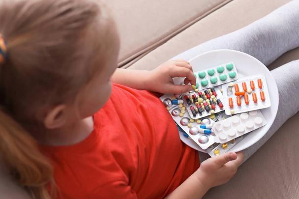 Little child with plate of different pills at home. Household danger - Foto, Imagen