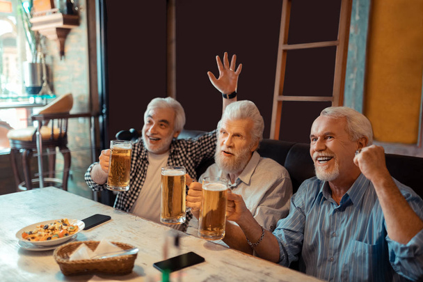 Three football fans drinking beer and watching football - Фото, зображення