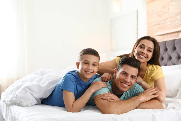 Happy young family together on large bed - 写真・画像