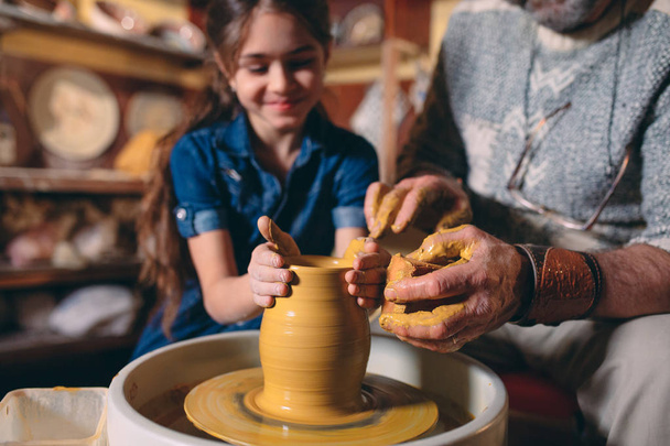 Pottery workshop. Grandpa teaches granddaughter pottery. Clay modeling - Photo, Image